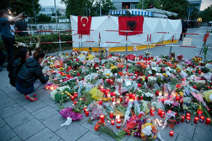 People mourn near the crime scene at OEZ shopping center the day after a shooting spree left at least nine people dead in Munich, Germany, on July 23, 2016.