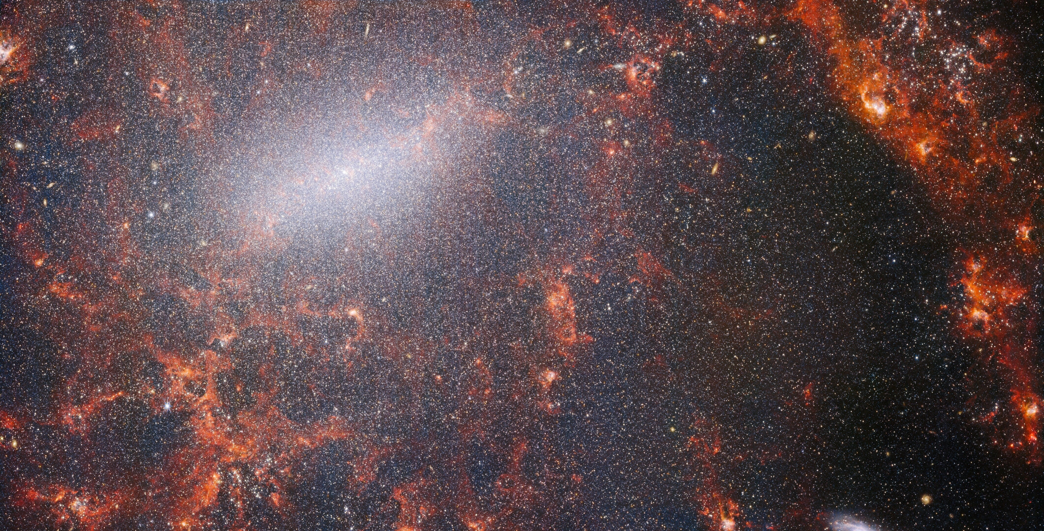 A delicate tracery of dust and bright star clusters threads across this image from the NASA/ESA/CSA James Webb Space Telescope. This view from Webbâ€™s NIRCam instrument is studded by the galaxyâ€™s massive population of stars, most dense along its bright central bar, along with burning red clouds of gas illuminated by young stars within. These glittering stars belong to the barred spiral galaxy NGC 5068, located around 17 million light-years from Earth in the constellation Virgo. This portrait of NGC 5068 is part of a campaign to create an astronomical treasure trove, a repository of observations of star formation in nearby galaxies. Previous gems from this collection can be seen here and here. These observations are particularly valuable to astronomers for two reasons. The first is because star formation underpins so many fields in astronomy, from the physics of the tenuous plasma that lies between stars to the evolution of entire galaxies. By observing the formation of stars in nearby galaxies, astronomers hope to kick-start major scientific advances with some of the first available data from Webb. The second reason is that Webbâ€™s observations build on other studies using telescopes including the NASA/ESA Hubble Space Telescope and some of the worldâ€™s most capable ground-based observatories. Webb collected images of 19 nearby star-forming galaxies which astronomers could then combine with catalogues from Hubble of 10 000 star clusters, spectroscopic mapping of 20Â 000 star-forming emission nebulae from the Very Large Telescope (VLT), and observations of 12Â 000 dark, dense molecular clouds identified by the Atacama Large Millimeter/submillimeter Array (ALMA). These observations span the electromagnetic spectrum and give astronomers an unprecedented opportunity to piece together the minutiae of star formation. This near-infrared image of the galaxy is filled by the enormous gathering of older stars which make up the core of NGC 5068. The keen vision of NIRCam allows astronomers to peer through the galaxyâ€™s gas and dust to closely examine its stars. Dense and bright clouds of dust lie along the path of the spiral arms: these are H II regions, collections of hydrogen gas where new stars are forming. The young, energetic stars ionise the hydrogen around them which, when combined with hot dust emission, creates this reddish glow. H II regions form a fascinating target for astronomers, and Webbâ€™s instruments are the perfect tools to examine them, resulting in this image. [Image Description: A close-in image of a spiral galaxy, showing its core and part of a spiral arm. At this distance thousands upon thousands of tiny stars that make up the galaxy can be seen. The stars are most dense in a whitish bar that forms the core, and less dense out from that towards the arm. Bright red gas clouds follow the twist of the galaxy and the spiral arm.] Links  NGC 5068 (NIRCam+MIRI Image) NGC 5068 (MIRI Image) Slider Tool (MIRI and NIRCam images) Video: Pan of NGC 5068 Video: Webb's views of NGC 5068 (MIRI and NIRCam images) Video: Zoom into NGC 5068 | DeviceDaily.com