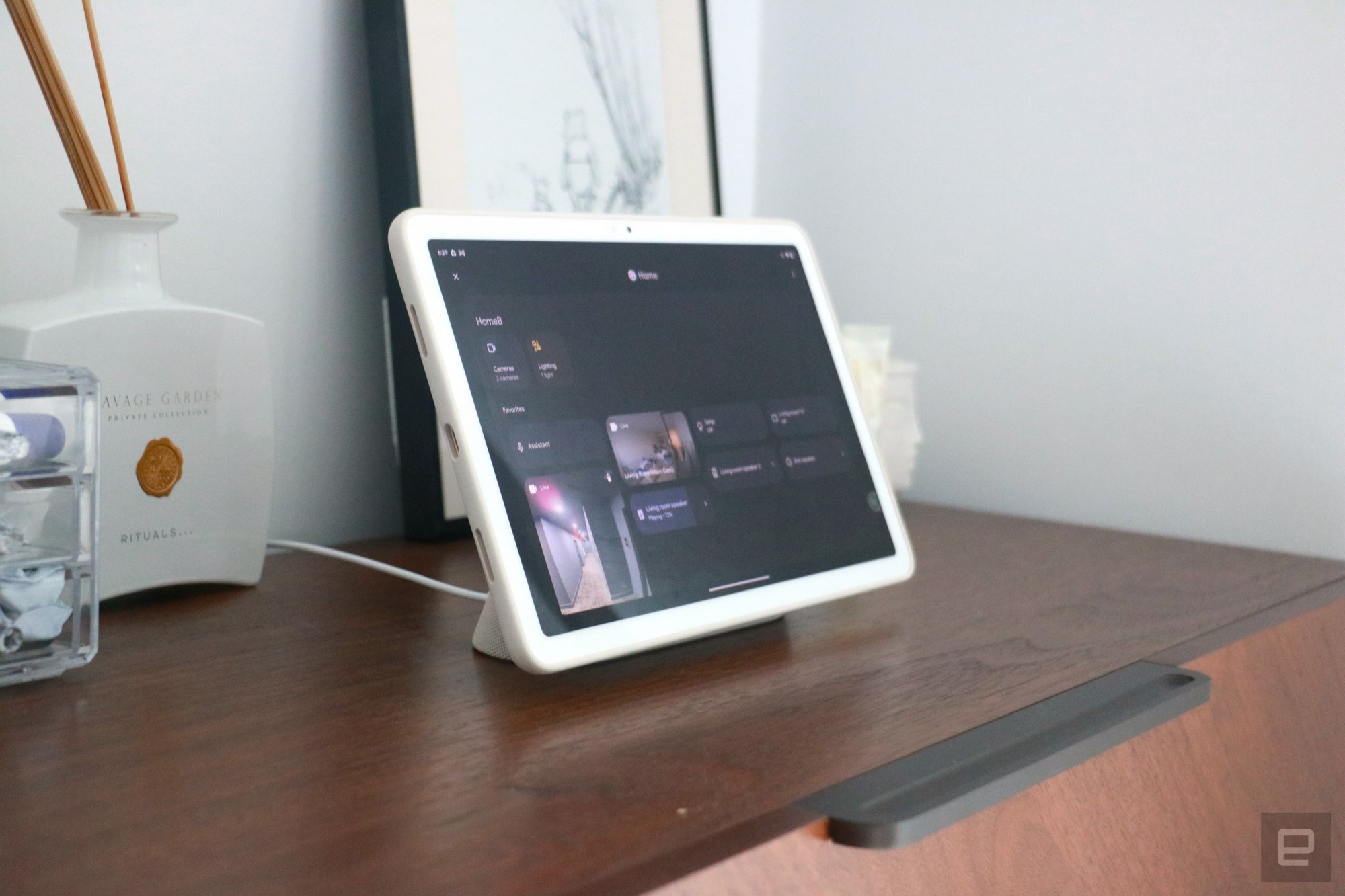 The Pixel Tablet on a walnut dresser showing the smart home dashboard in Hub Mode. | DeviceDaily.com