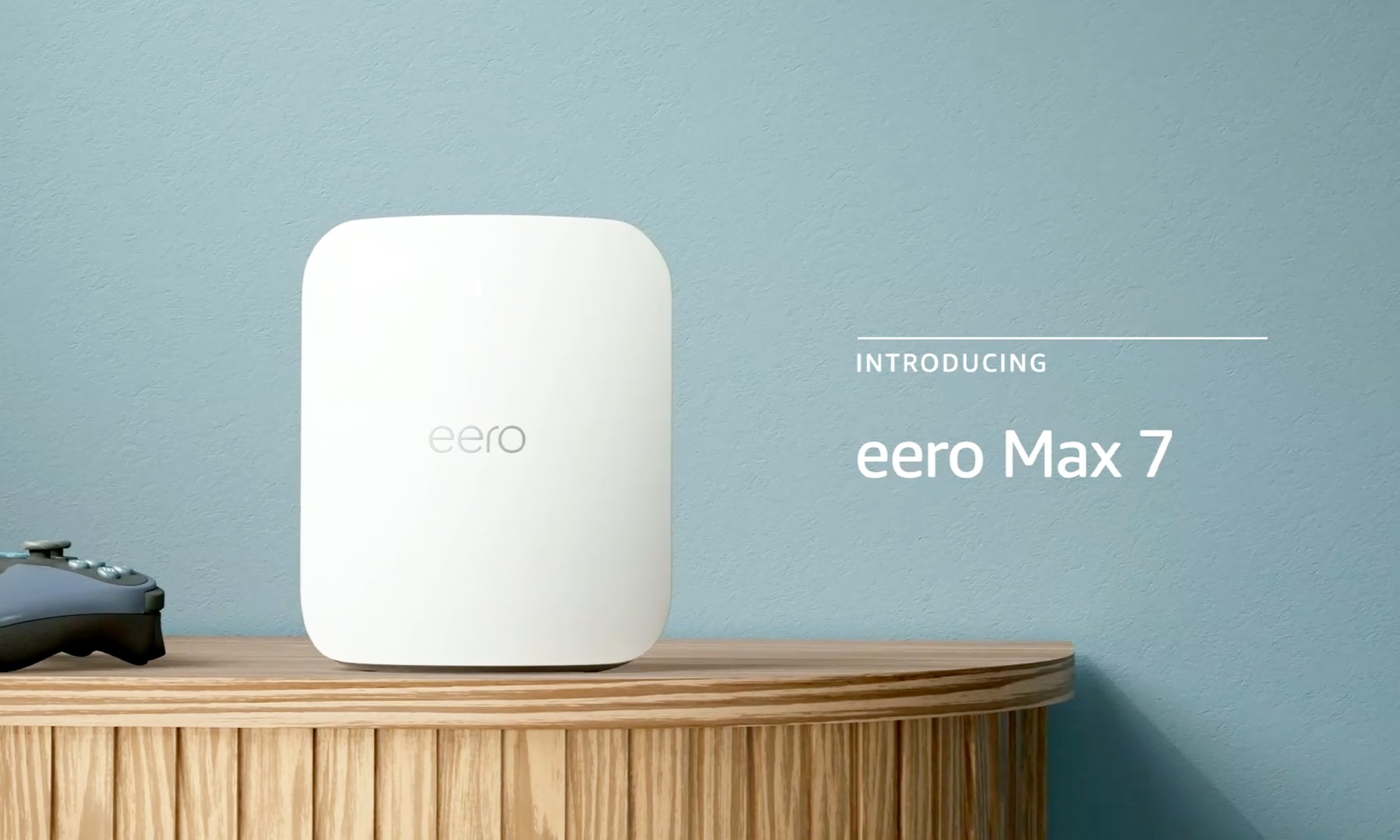 Amazon product photo of the Eero Max 7 Wi-Fi router. It sits on a stand next to a gaming controller. The superimposed text | DeviceDaily.com