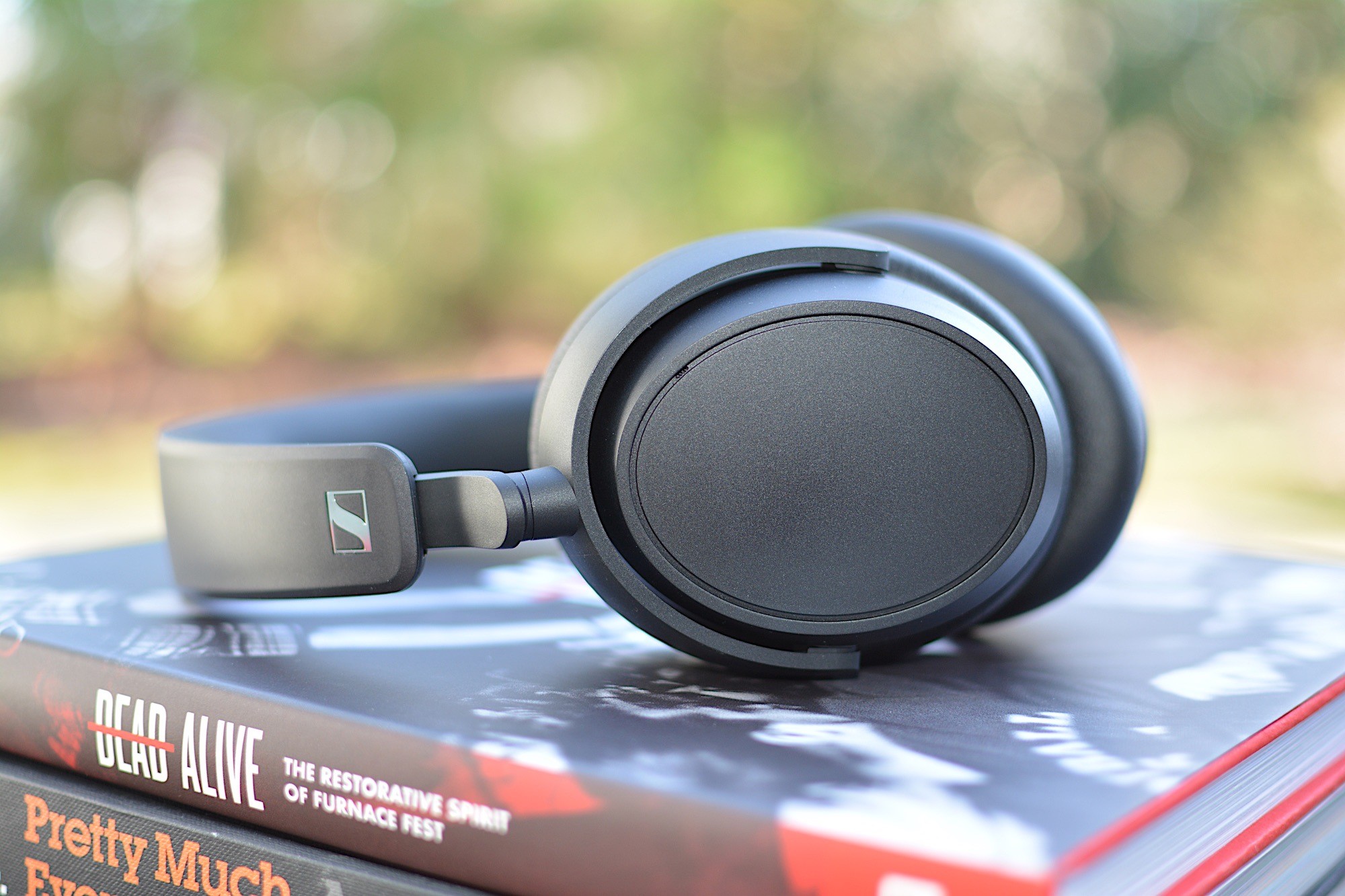 Sennheiser Accentum Plus headphones from the side, laid flat on two books. | DeviceDaily.com